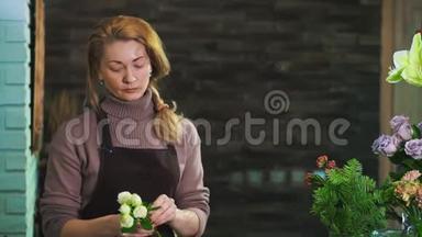 一个穿着围裙的女花匠，站在一家花店的柜台上，准备一束花。